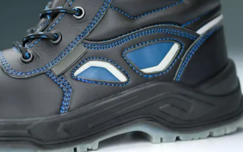 Bota de trabajo negra con costuras azules y detalles en azul y blanco. La suela tpu ofrece agarre y durabilidad para cualquier terreno.