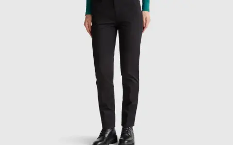 Mujer con pantalones chinos negros y botines gruesos. Un look moderno y versátil.