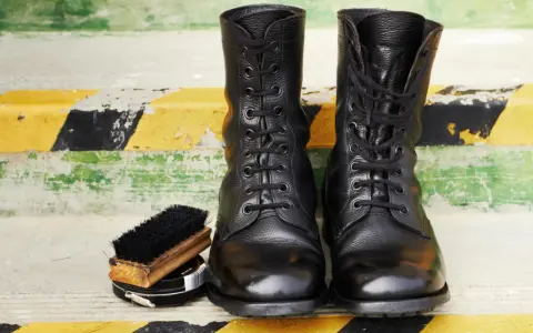 Botas militares negras, cepillo y betún. Aprende como limpiar botas militares para que luzcan impecables.