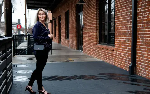 Mujer con outfit de camisa azul a rayas, pantalones negros y zapatos de tacón.
