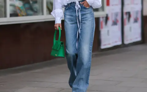 Mujer con vaqueros anchos, talla 30 pantalón equivalencia España, y bolso verde.