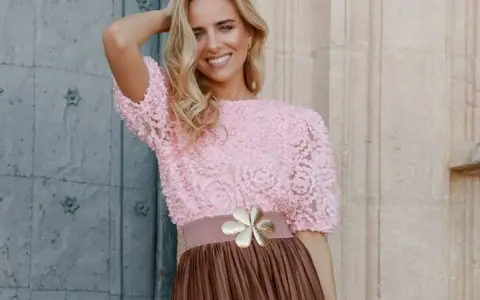 Mujer sonriente con top rosa de encaje y falda marrón, ideal para una boda en octubre, manga corta o larga.