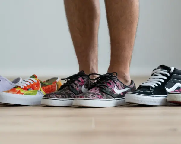 Un hombre elige entre varias zapatillas de **material canvas**. Hay modelos de colores, estampados florales, de cuadros y lisos.