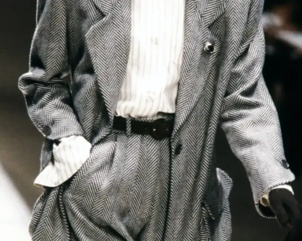 Un elegante power suit de espiga gris con camisa a rayas y cinturón negro.