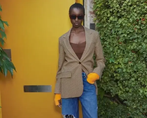 Mujer con blazer de cuadros, top marrón y vaqueros rotos. Ideas de qué ponerse debajo de una blazer para un look moderno.