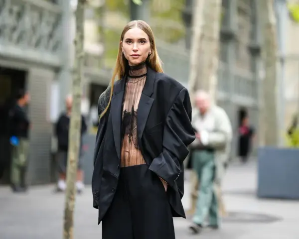 Mujer con traje negro y top transparente, ideal para saber como ir vestida a un cóctel de tarde.
