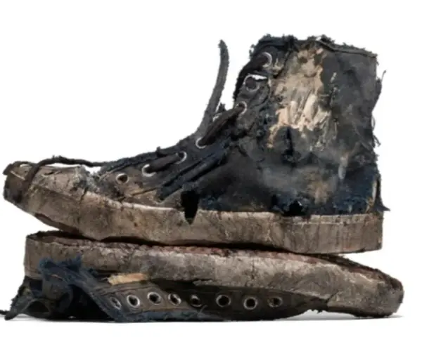 Un par de zapatillas gastadas, rotas y sucias, apiladas una sobre otra. Parecen haber vivido muchas aventuras.