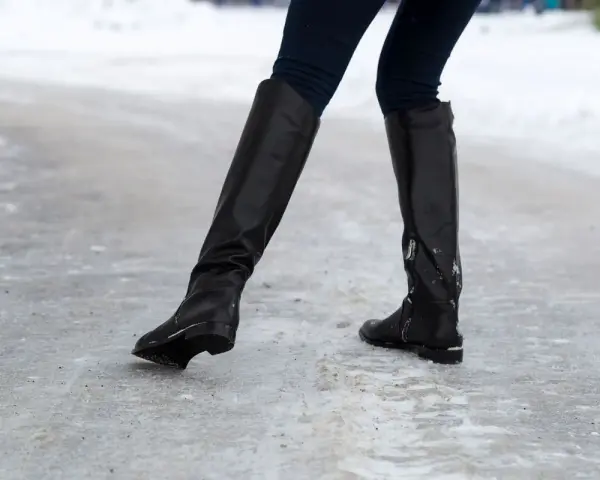 Botas negras sobre hielo. ¿Qué hacer para que no resbalen los zapatos? Evita caídas con buen calzado.