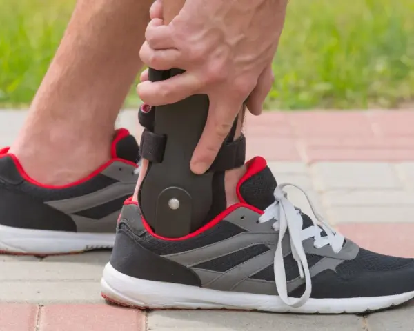 Persona ajustando un soporte para el tobillo dentro de un zapato deportivo, ideal para saber qué zapatos usar después de una fractura de tobillo.