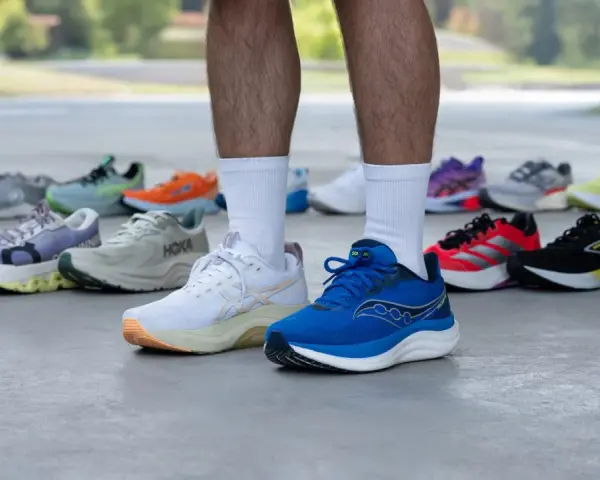 Un corredor muestra varias zapatillas deportivas, buscando el mejor calzado para tendinitis aquiles.
