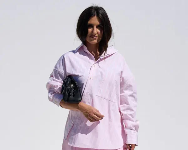 Mujer con una camisa rosa a rayas y un bolso negro.