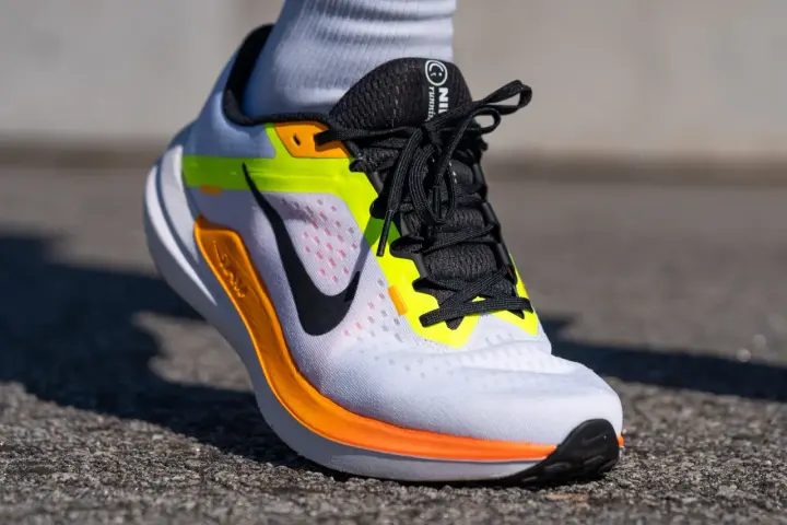 Zapatillas Nike Winflo 10 blancas con detalles en naranja y neón, listas para correr.