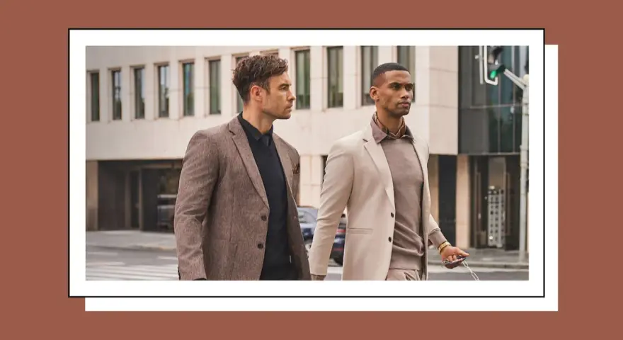 Dos hombres con trajes elegantes caminan por la calle. Uno lleva un traje beige y el otro un traje marrón.