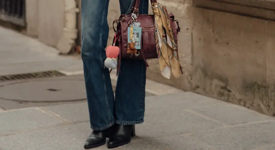 Botas negras elegantes con tacón, perfectas para complementar unos pantalones vaqueros anchos y un bolso de cuero con adornos.
