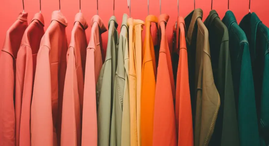 Percheros con ropa de tonos cálidos y fríos, un arcoíris de color verano listo para usar.