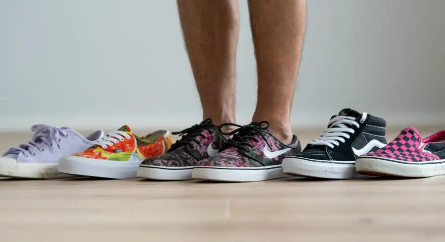 Un hombre elige entre varias zapatillas de **material canvas**. Hay modelos de colores, estampados florales, de cuadros y lisos.