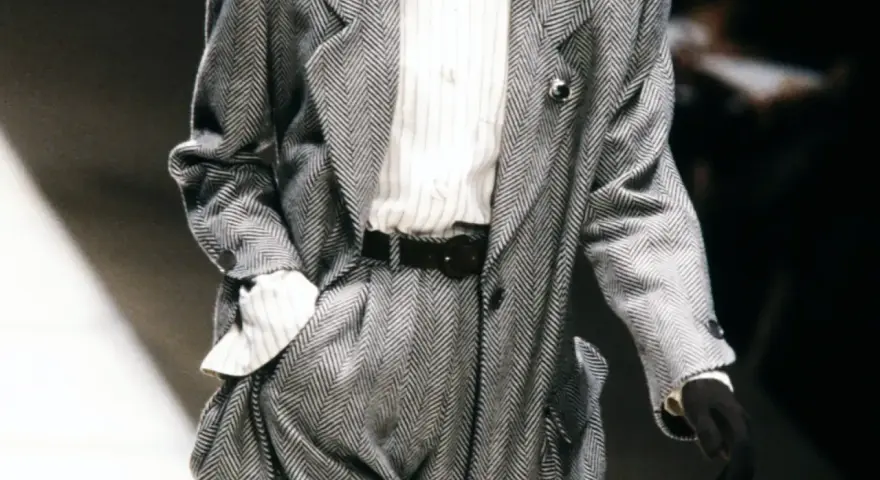 Un elegante power suit de espiga gris con camisa a rayas y cinturón negro.