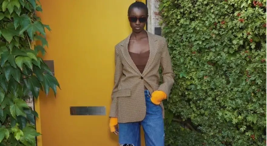 Mujer con blazer de cuadros, top marrón y vaqueros rotos. Ideas de qué ponerse debajo de una blazer para un look moderno.