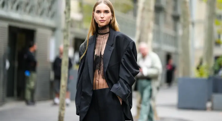 Mujer con traje negro y top transparente, ideal para saber como ir vestida a un cóctel de tarde.