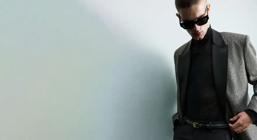 Joven con gafas de sol y traje elegante, listo para una **nochevieja en casa** con estilo.