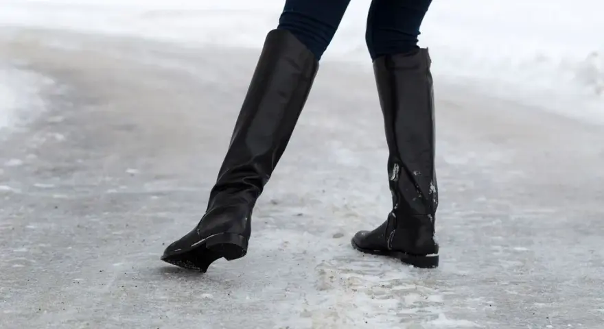 Botas negras sobre hielo. ¿Qué hacer para que no resbalen los zapatos? Evita caídas con buen calzado.