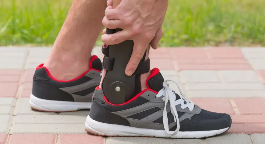 Persona ajustando un soporte para el tobillo dentro de un zapato deportivo, ideal para saber qué zapatos usar después de una fractura de tobillo.