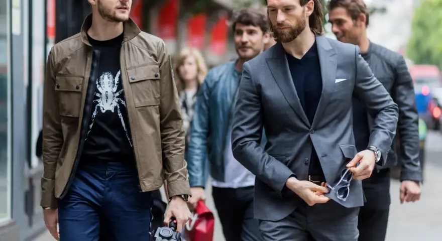 Hombres con estilo, uno con chaqueta y camiseta estampada, otro con traje gris. Dress code casual.