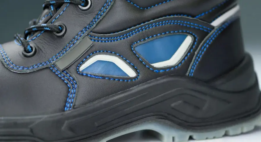 Bota de trabajo negra con costuras azules y detalles en azul y blanco. La suela tpu ofrece agarre y durabilidad para cualquier terreno.