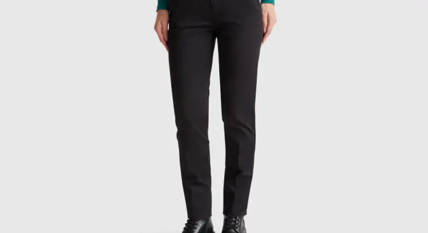 Mujer con pantalones chinos negros y botines gruesos. Un look moderno y versátil.