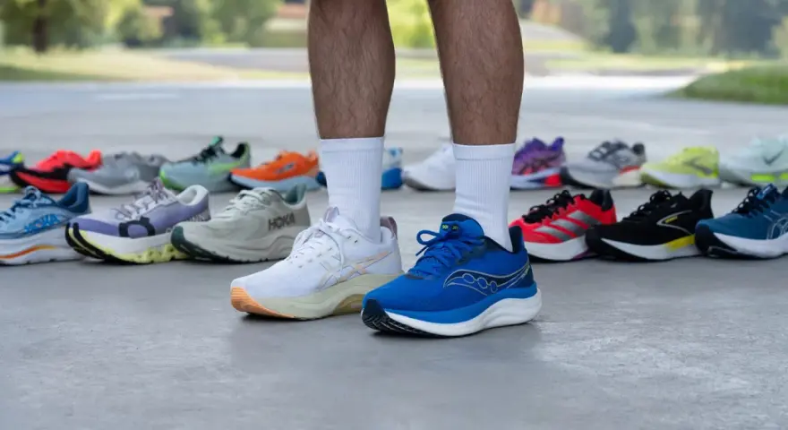 Un corredor muestra varias zapatillas deportivas, buscando el mejor calzado para tendinitis aquiles.