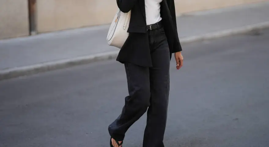 Look con blazer negro y jeans grises anchos. Bolso blanco y sandalias negras completan el atuendo.