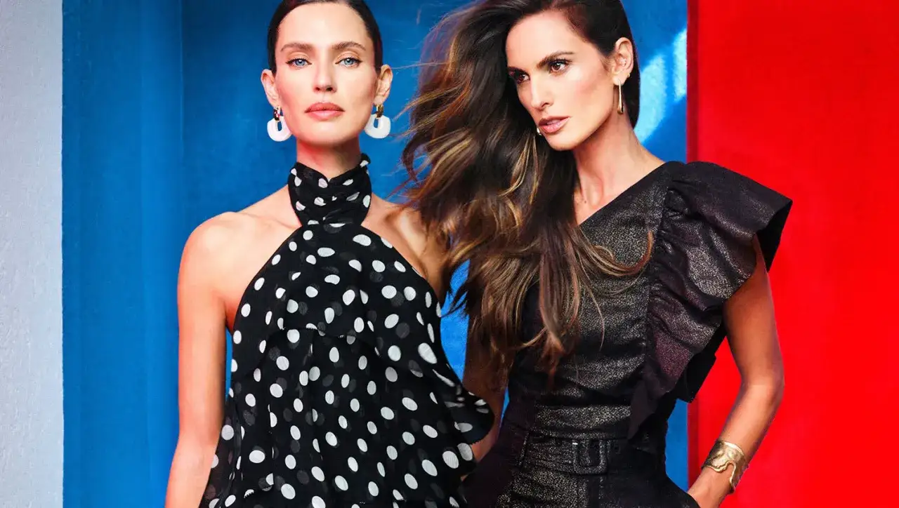 Dos mujeres posan con elegantes vestidos, ideales para un dress code cocktail Espa&ntilde;a.