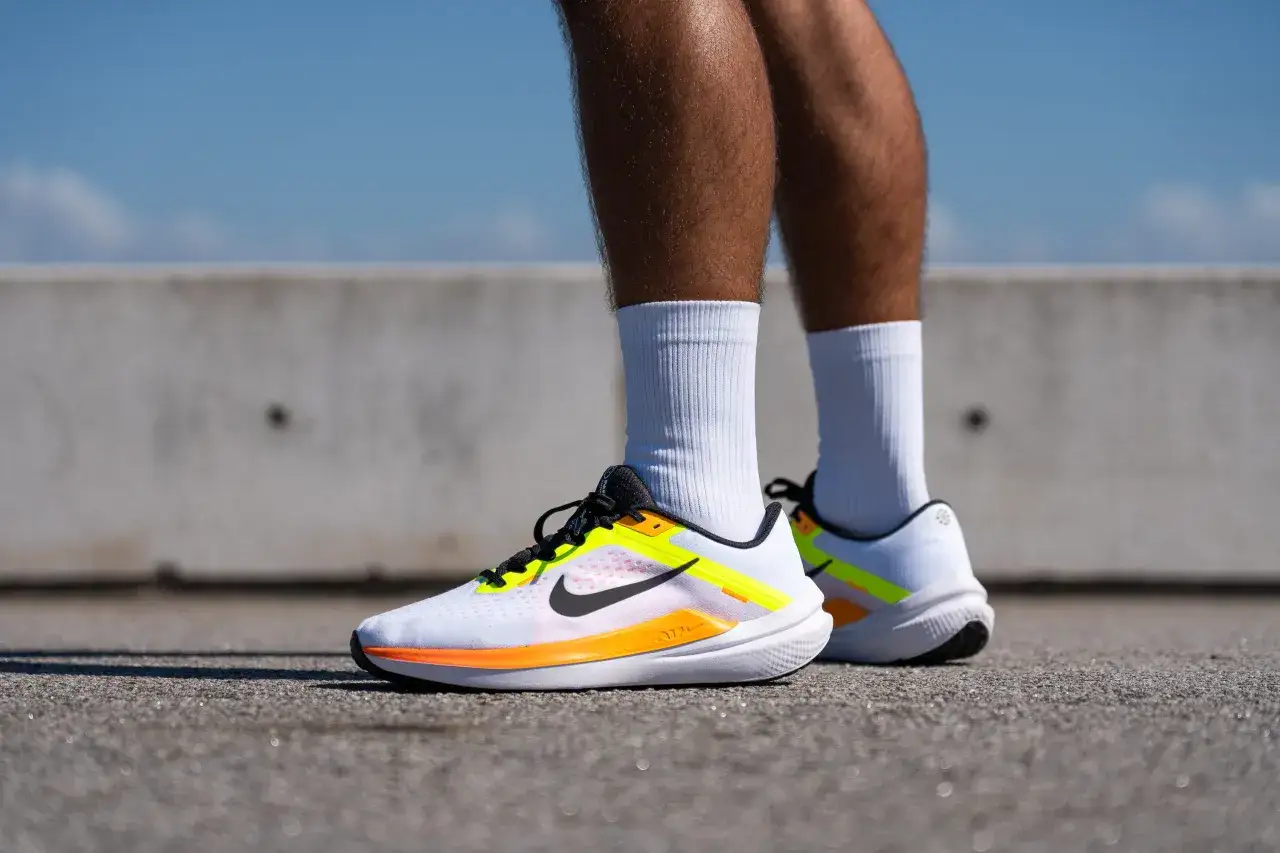 Zapatillas de running blancas con detalles en naranja y amarillo neón, modelo Winflo 10, listas para la acción.