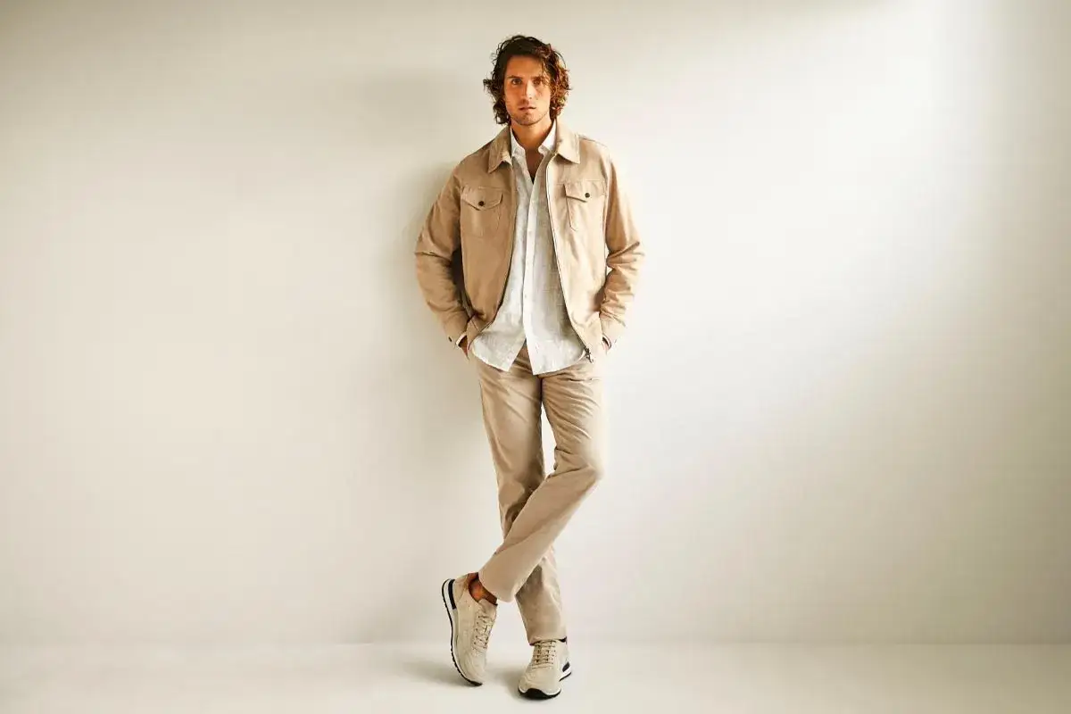 Hombre con chaqueta beige, camisa blanca y pantalones caqui. Un look perfecto para un dress code casual.