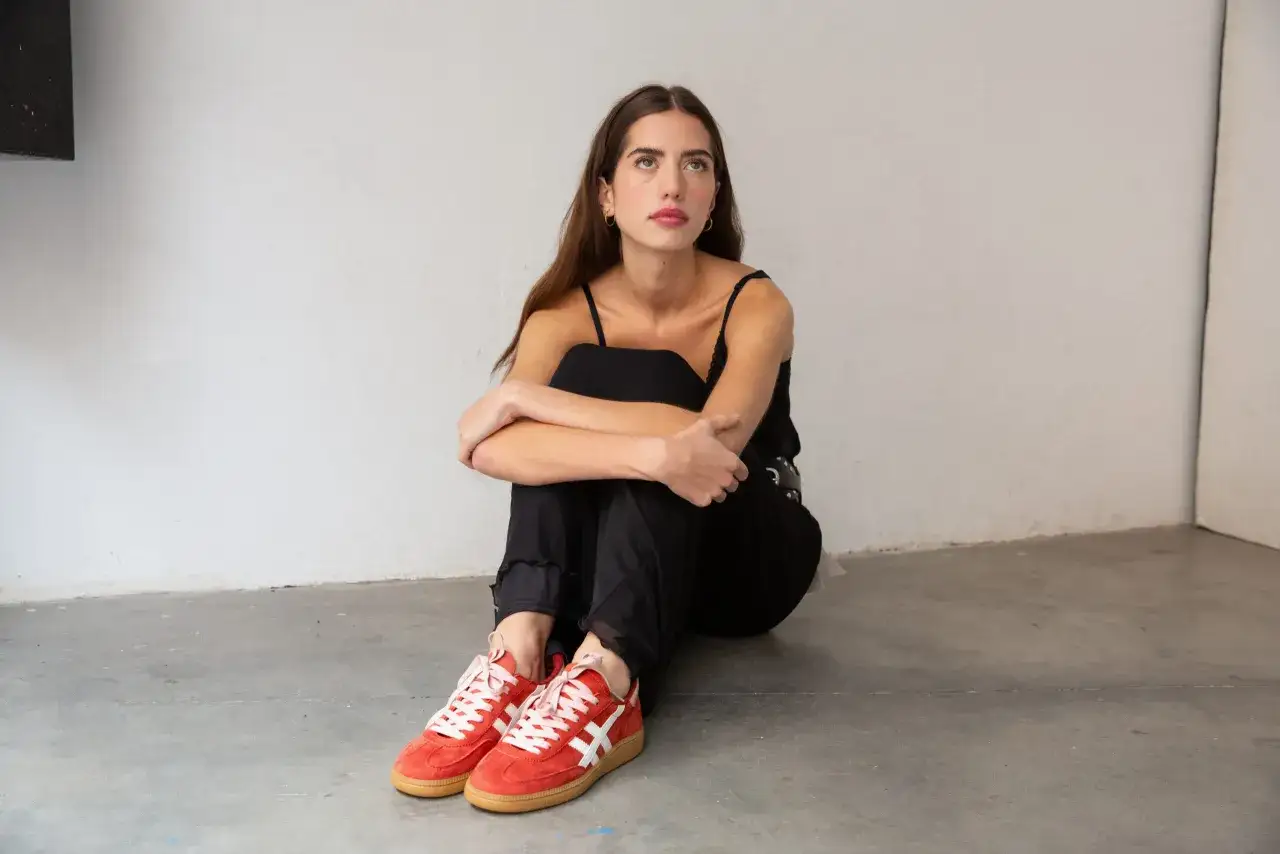 Mujer con zapatillas rojas vibrantes, evocando los colores primavera, sentada en el suelo.