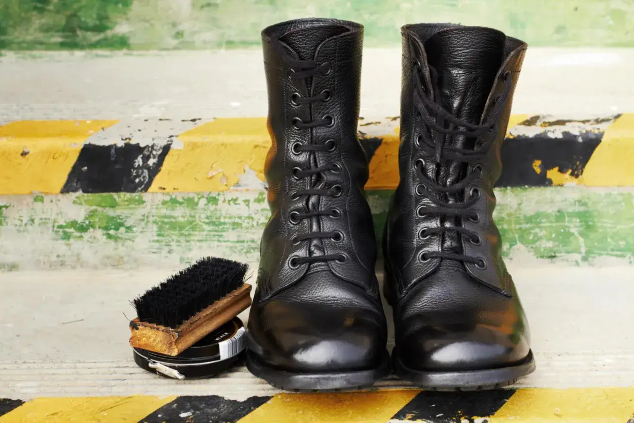 Botas militares negras, cepillo y bet&uacute;n. Aprende como limpiar botas militares para que luzcan impecables.