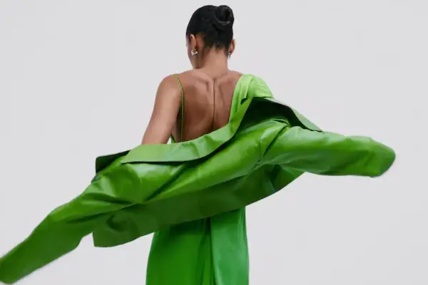Mujer con un vestido verde brillante y una chaqueta verde vibrante. Un look audaz para combinar vestido verde con chaqueta.