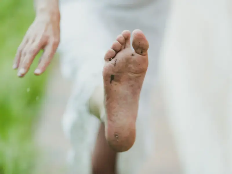 Pie sucio y descalzo, con tierra y hierba. Un consejo para como quitar el olor de los pies es lavarlos bien.